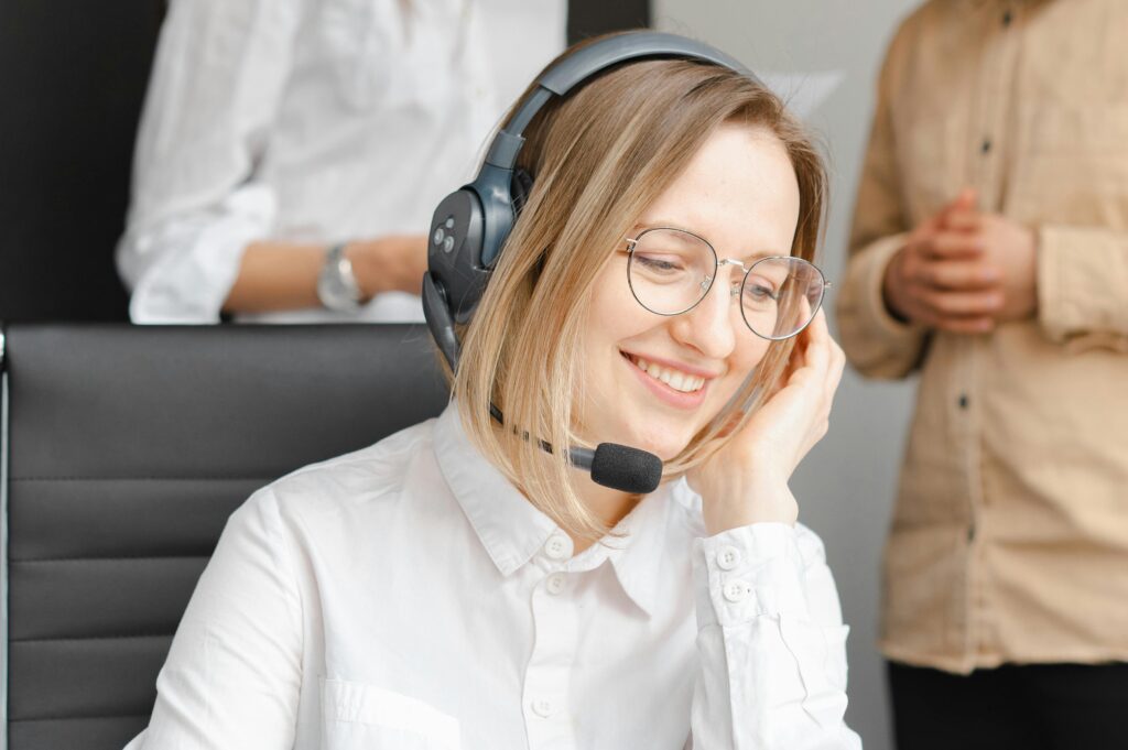 A friendly call answering professional wearing a headset and smiling while taking a call