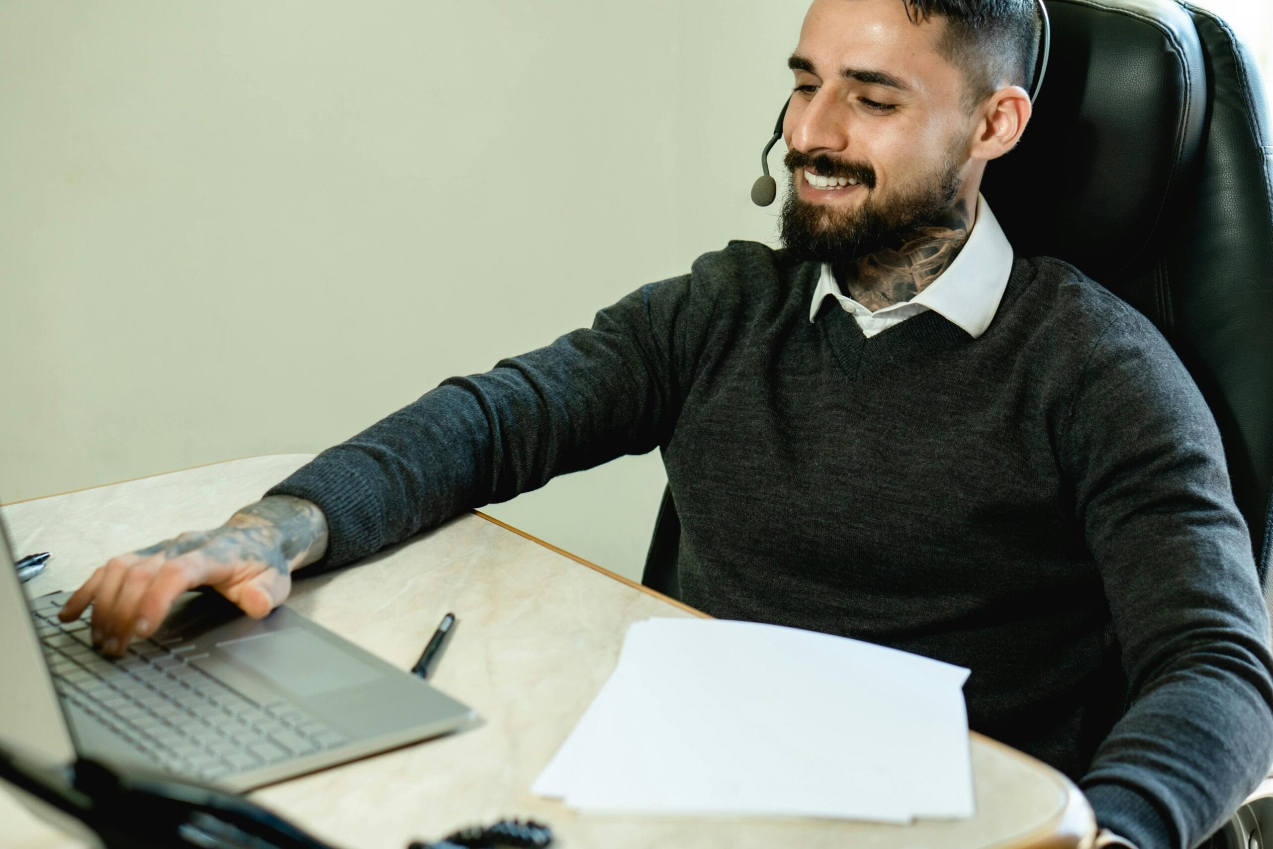 Man with a beard at a desk using a laptop, representing a Virtual Receptionist in a professional setting.